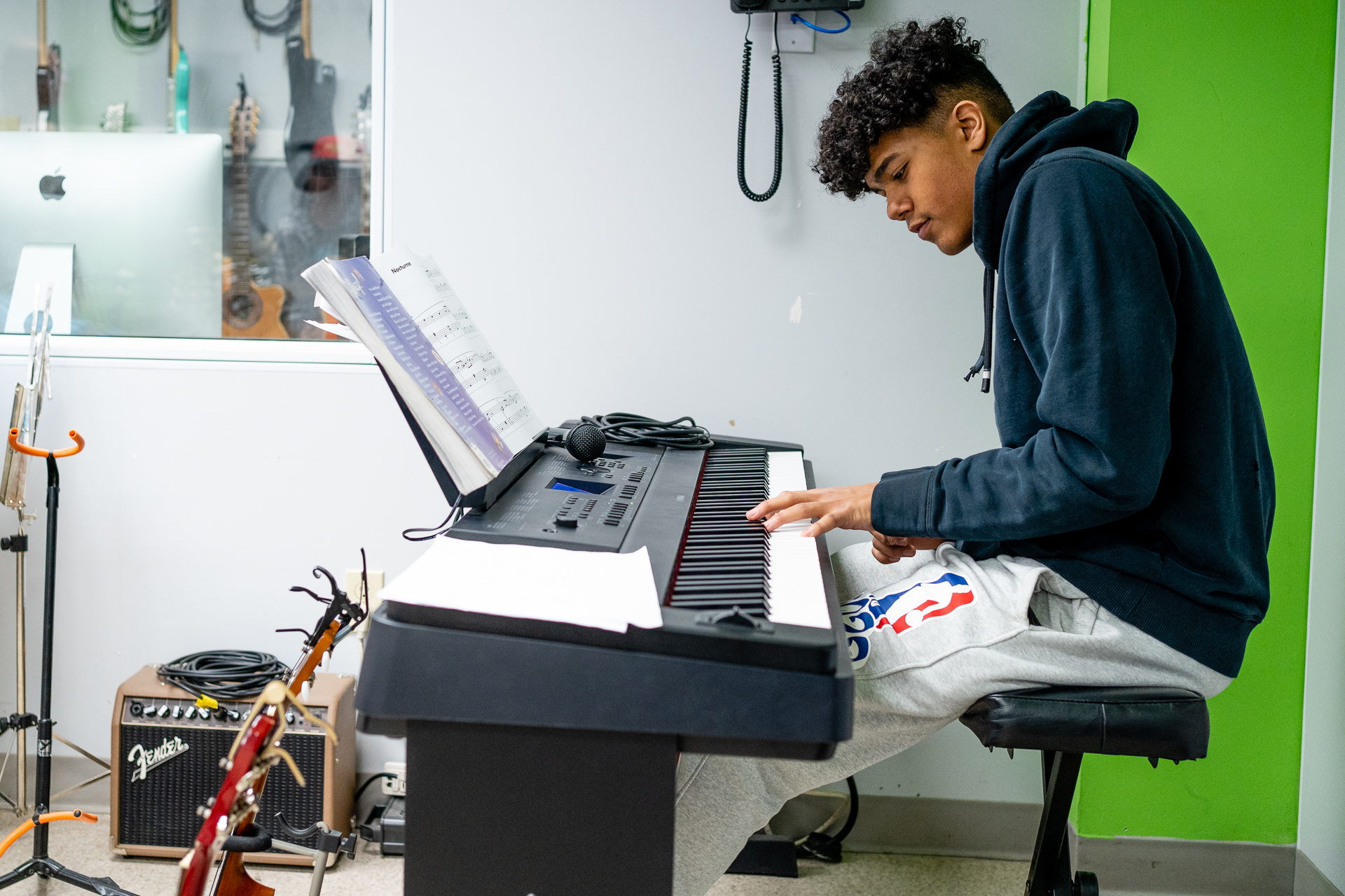 18-year-old Evan practices piano in the music studio at Teen Stop Jeunesse