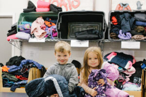 5-year-old Hudson sits with his 3-year-old sister and a mountain of winter coats.