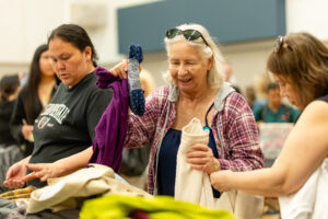 Three women sift through donated clothing at Women's Day of Caring 2026.