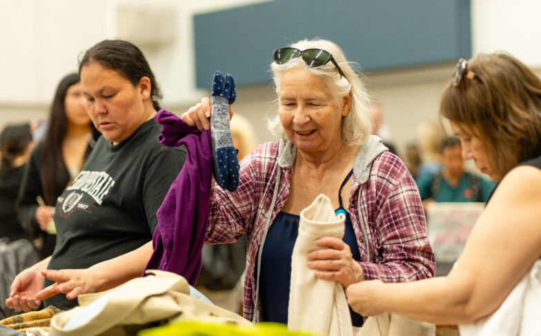 Three women sift through donated clothing at Women's Day of Caring 2026.